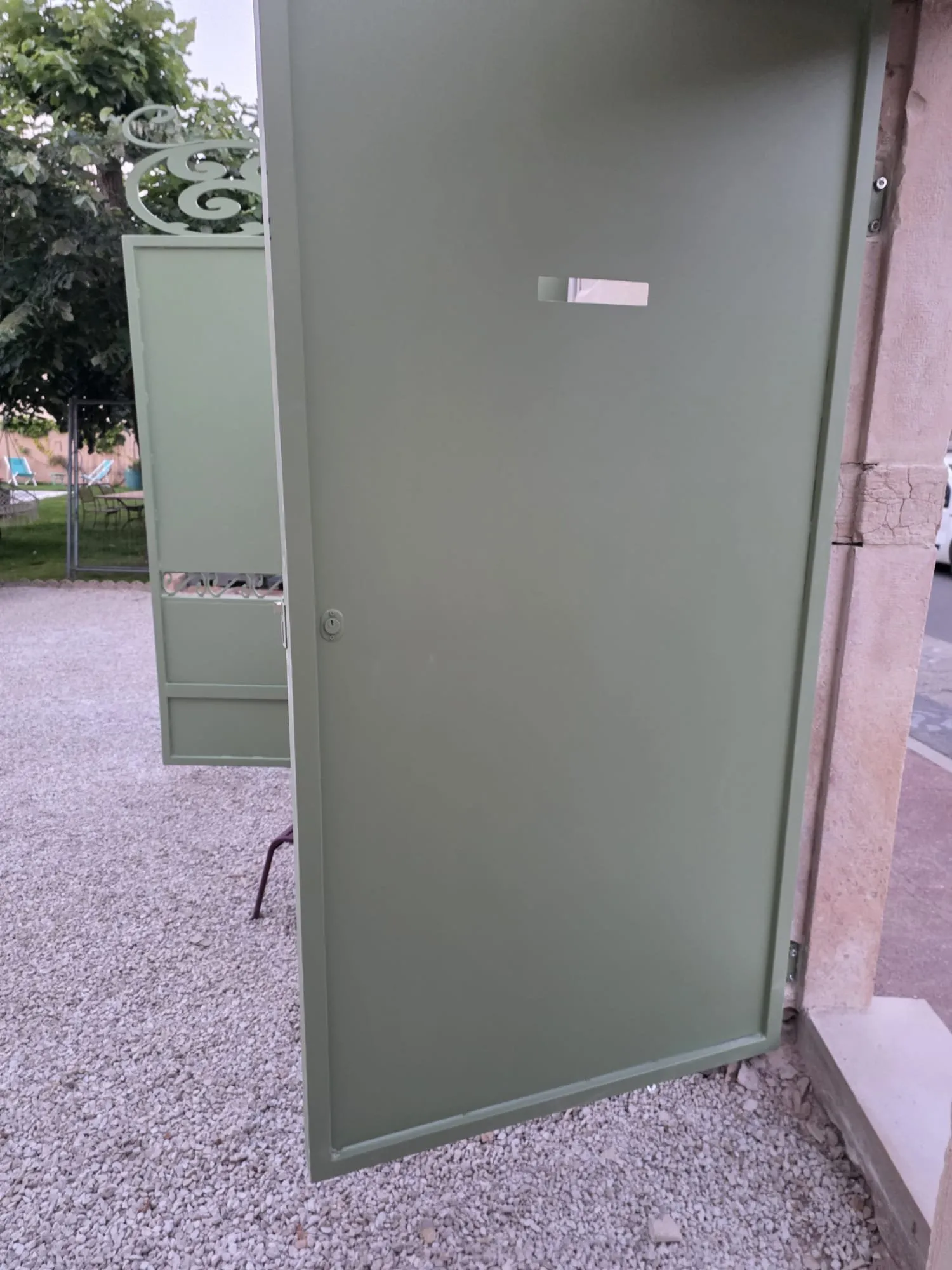Portillon acier ouvert sur allée gravillonnée