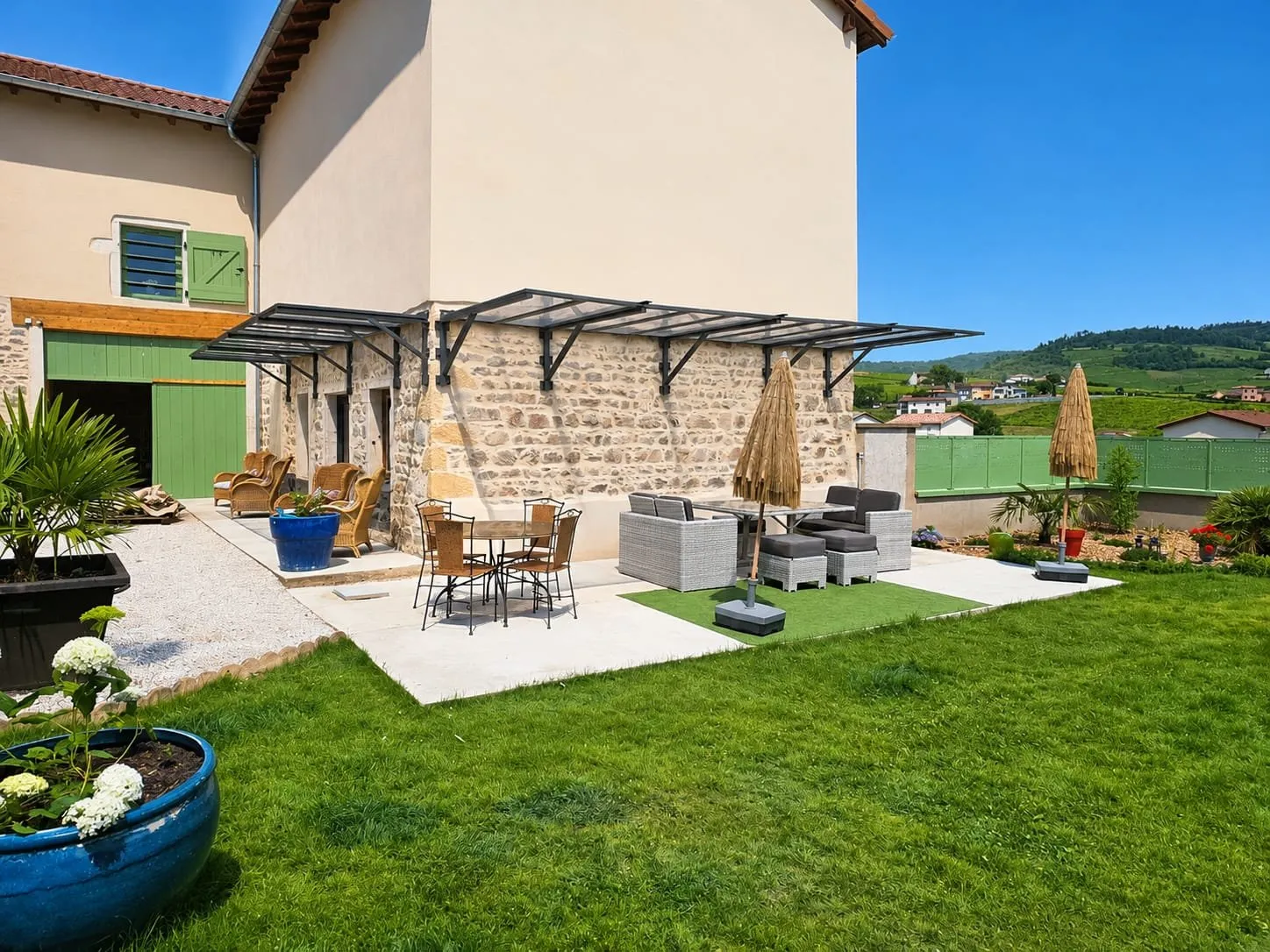 Pergola acier sur maison en pierre et jardin aménagé